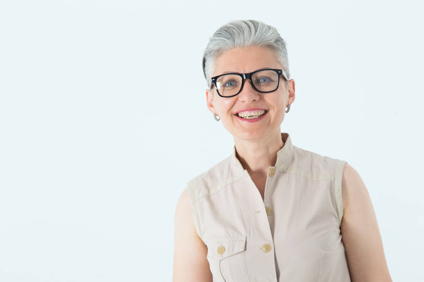 Portrait of a beautiful mature woman in glasses on a light background. - Foto, Imagen