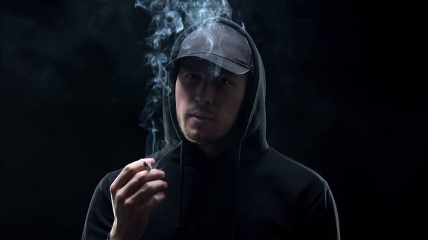 Gangster in black holding cigarette and looking camera, banditry racketeering - Fotó, kép