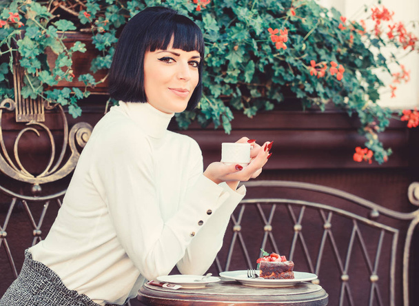 Pleasant time and relaxation. Delicious and gourmet drink. Girl relax cafe with coffee and dessert. Woman attractive elegant brunette enjoy gourmet coffee cafe terrace background. Gourmet concept - 写真・画像