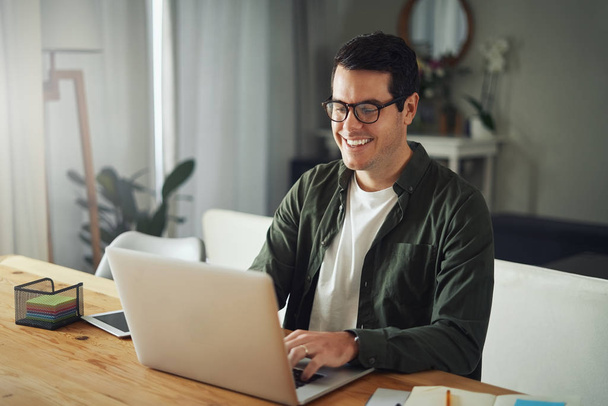 Happy man wearing eyeglasses using laptop at home - Foto, Bild
