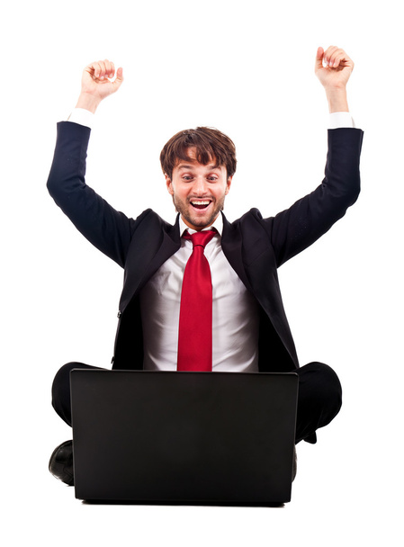 Victorious businessman with arms raised sitting in front of his laptop isolated on white - Foto, Imagem