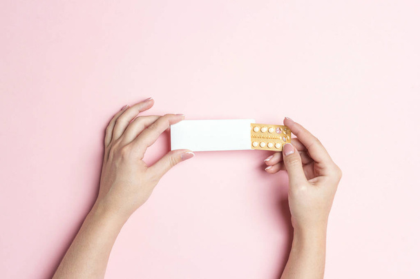 Female hands holding birth control pills on pink background. Wom - Φωτογραφία, εικόνα