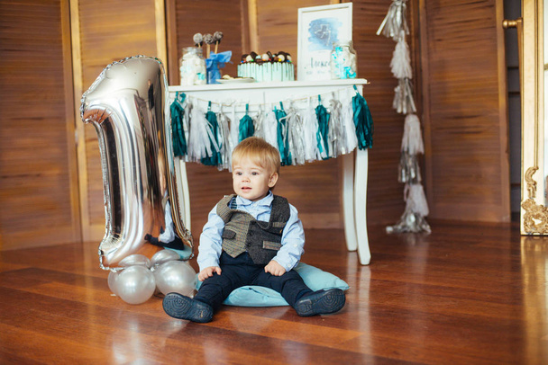 Cute little boy on his first birthday with a candy bar and colorful balloons - Foto, Imagem