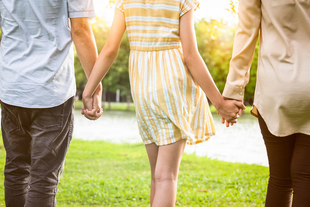 Rear view of asian family,closeup hands of father,mother,daughter holding hands and walking in nature,dad,mom,child girl enjoying at outdoor park in summer,loving parents,girl spending time together,family relationship,happiness - Photo, Image