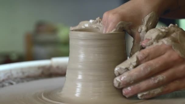 陶芸家の車輪に取り組む女性手は粘土鍋からカップを彫刻します。ポッターホイールスローモーションのモデリングに関するワークショップ - 映像、動画