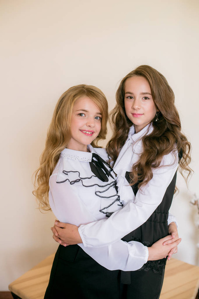 Dwa słodkie dziewczyny uczennice z długimi kręcone włosy w modnej szkole ubrania. Moda szkolna w stylu Vintage Elite. - Zdjęcie, obraz