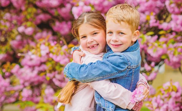 Love is in the air. Romantic babies. Couple kids walk sakura tree garden. Tender love feelings. Little girl and boy. Romantic date. Spring time to fall in love. Kids in love pink cherry blossom - Photo, Image