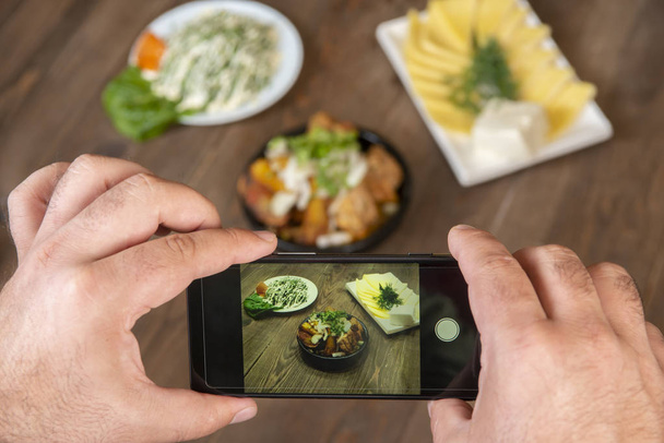 Food blogger using smartphone taking photo .Mans hands make phone photography of traditional meals. lunch or dinner.meat and potatoes. For social media, blogging. Top view mobile phone. - Foto, imagen