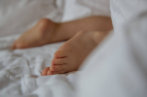 Baby feet on white sheet - Фото, изображение