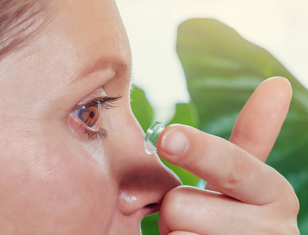 Женщина вставляет контактную линзу в глаз
. - Фото, изображение