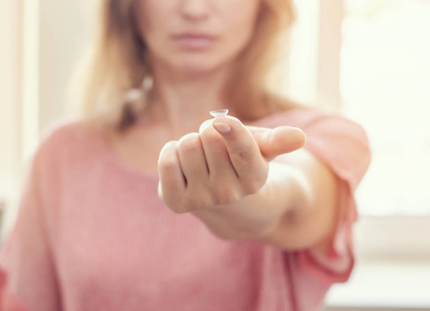 Frau zeigt Kontaktlinse an Spitze des ausgestreckten Fingers. Optik - Foto, Bild