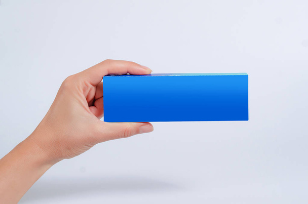 Main féminine tenir une tablette bleue, carte de visite, boîte sur un fond blanc
. - Photo, image