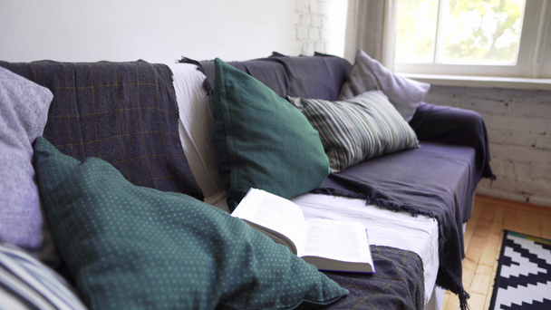 Κοντινό πλαίσιο ενός καναπέ δίπλα στο παράθυρο, ένα άνετο εσωτερικό σε φυσικά υλικά στο σχεδιασμό - Πλάνα, βίντεο