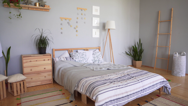 Bedroom set with cozy accessories in the Scandinavian style. A bed with a large number of pillows, soft carpets and blankets. - Footage, Video