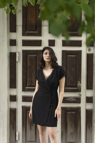 Beautiful brunette girl, wearing a black dress with a deep neckl - Fotó, kép