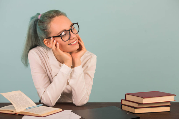 beautiful young woman in glasses sits at a table with books - Photo, image