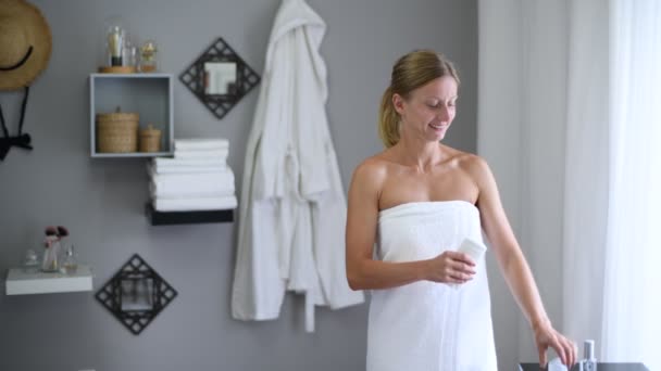 Body care. Beautiful woman wrapped in towel after shower is using antiperspirant. - Filmmaterial, Video