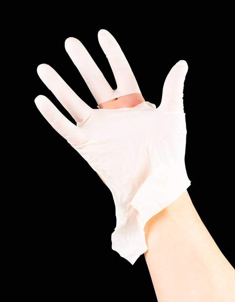 黒い背景に隔離された白人の手に壊れた白いラテックス外科医の医学手袋 - 写真・画像