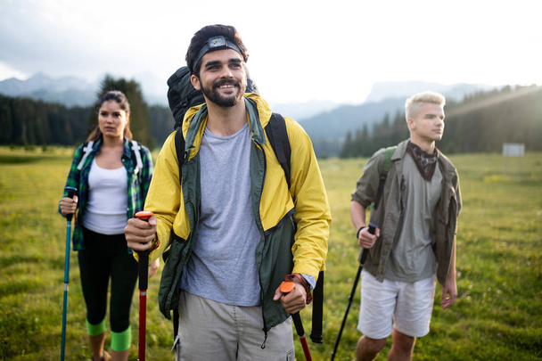 Hiking with friends is so fun. Group of young people with backpacks walking together and looking happy - Photo, image