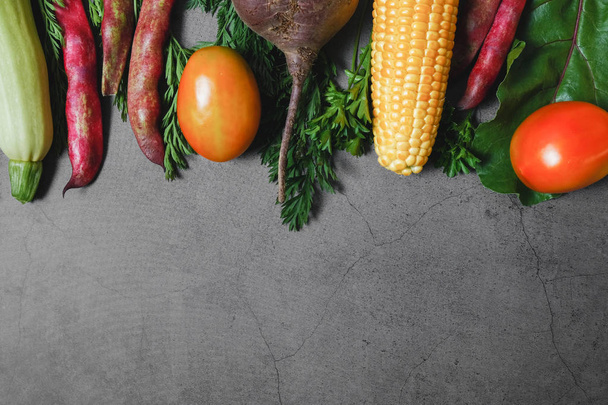Assorted fresh vegetables on a black background. Corn, tomatoes, zucchini, carrot, beetroot, garlic, bean. Food concept. Flat lay, top view, copy space - Photo, image