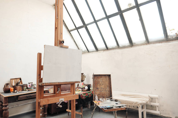 Bright art studio with a large window. Easels and canvases. - 写真・画像