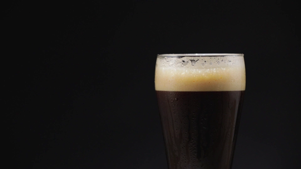 Studené tmavé pivo ve sklenici s kapkami vody - Záběry, video