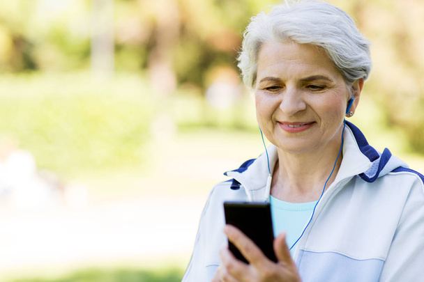 sporty senior woman with earphones and smartphone - Foto, Imagem