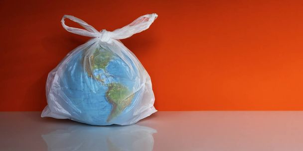 Earth globe in plastic bag on grey background - Photo, Image