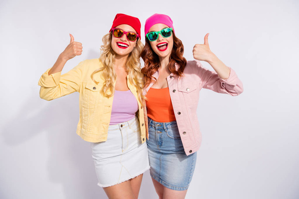 Photo of two pretty ladies raising thumbs up wear sun specs casual clothes isolated white background - Zdjęcie, obraz