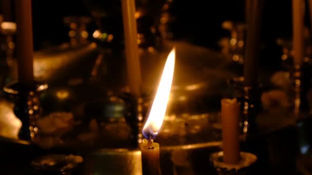 Subtiele kerk kaarsen branden in een orthodoxe christelijke kerk in de buurt van heilige beelden in de donkere close-up, gefilmd met behulp van zoomen en het verplaatsen van de camera - Video