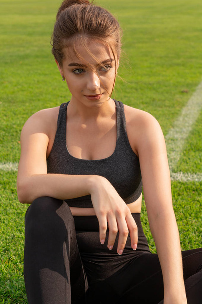 sexy atlético menina sentado no grama em um estádio
 - Foto, Imagem