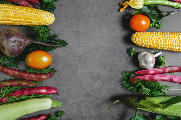 Assorted fresh vegetables on a black background. Corn, tomatoes, zucchini, carrot, beetroot, garlic, bean. Food concept. Flat lay, top view, copy space - Foto, Imagem
