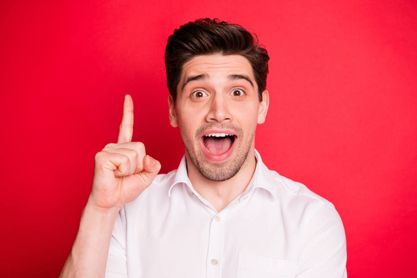 Close up photo of impressed worker raising his index finger screaming wow omg wearing white t-shirt isolated over red background - Fotoğraf, Görsel