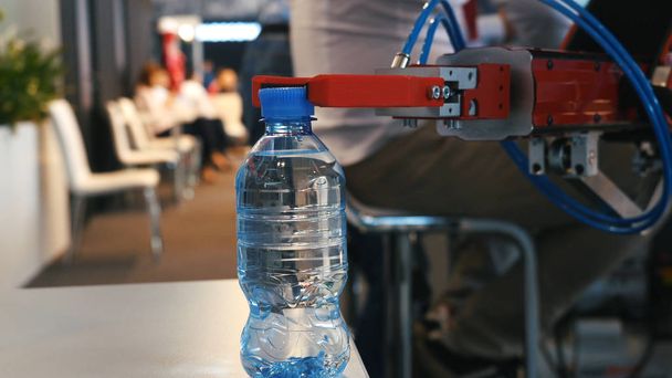 Close-up van robot hand holding en het verhuizen van een fles met water op de tentoonstelling. Media. Verschillende werken robots collectie gepresenteerd op de Robotics forum tentoonstelling - Foto, afbeelding