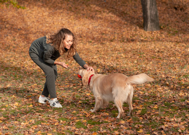 Egy fiatal nő játszik a kutyájával a parkban. - Fotó, kép
