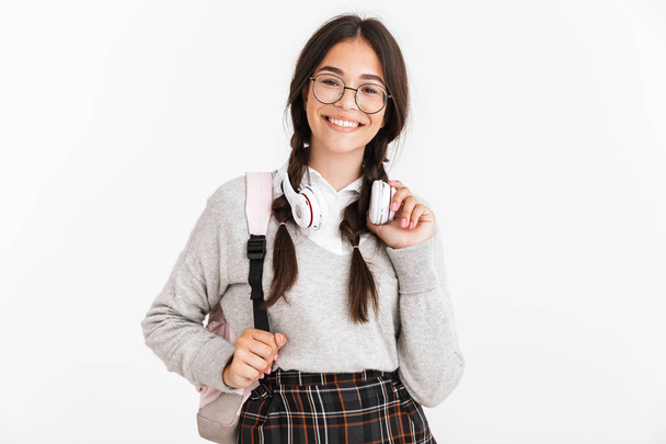 Excited emotional young school girl isolated over white wall background with headphones posing. - Zdjęcie, obraz