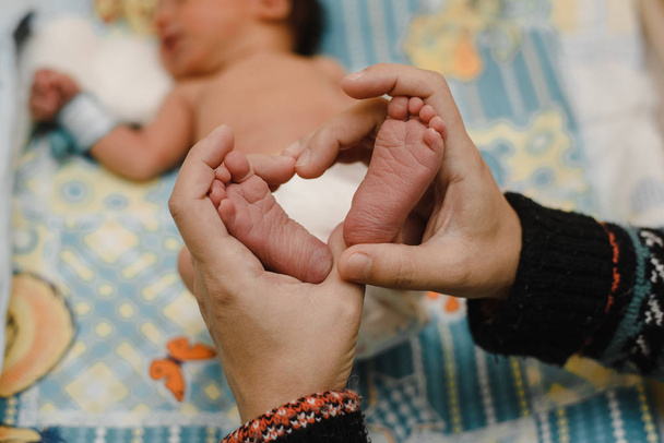 lábát egy újszülött a kezében a szülők. A szeretet, az egészséges szülés és a boldog fiatal szülők fogalma - Fotó, kép