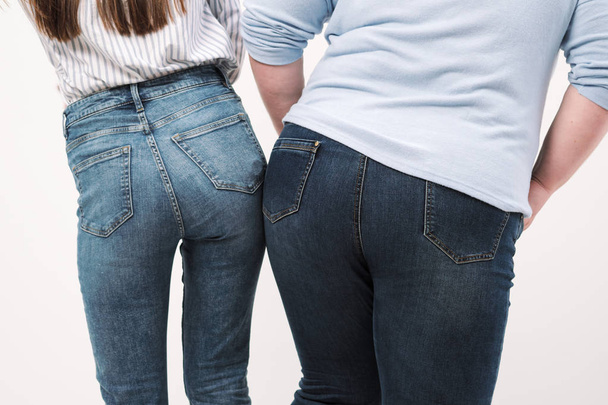 Two girls, fat and slender, show the backs of their ass into the camera. Comparison of two butts. - Zdjęcie, obraz