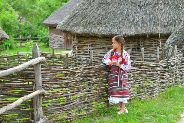portrait of Ukrainian Beautiful girl in vyshivanka next to the old wooden house . girl in embroidery.Concept of national traditions - Photo, Image
