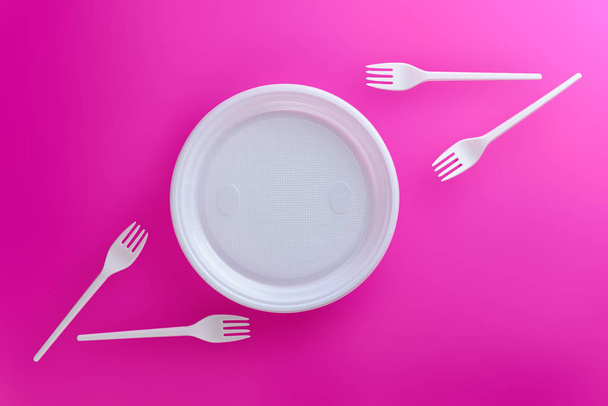 White plastic dishes on a pink background. Flat lay, horisontal orientation. - Photo, Image