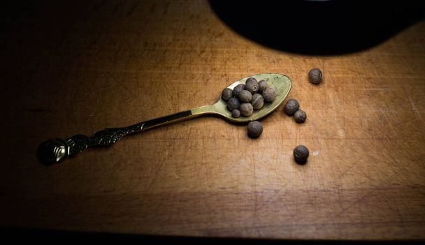 Black pepper on a spoon on a wooden board - Photo, Image