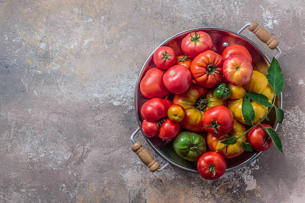 Ripe tomatoes in a pan on stone background, copy space - Photo, Image