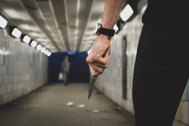 犯罪強盗の概念。トンネル内で殺人を犯す鋭いナイフを持つ強盗または殺人者 - 写真・画像
