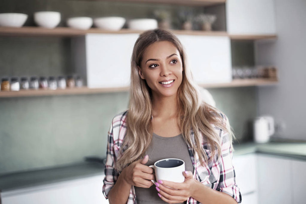cute young woman with mug standing in kitchen - Foto, immagini