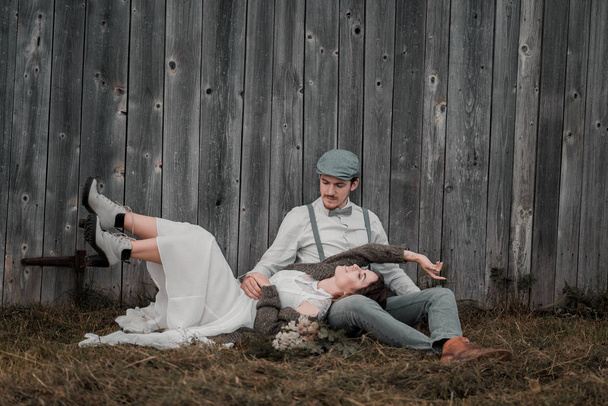 recién casados vestidos en estilo vintage cerca de la pared de madera gris
 - Foto, Imagen
