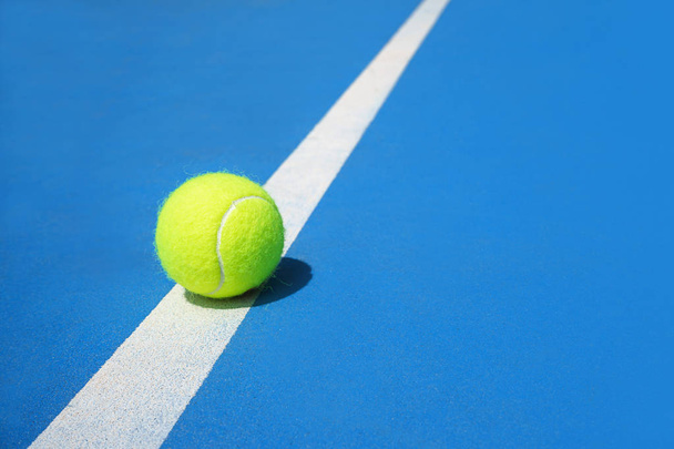 Summer sport concept with tennis ball on white line on hard tennis court blue color. - Fotografie, Obrázek