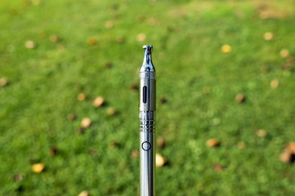 Cigarro eletrônico com óleo de cannabis sobre fundo natural desfocado
 - Foto, Imagem