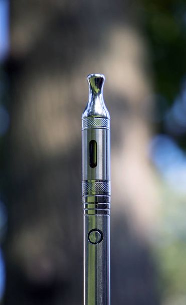Electronic cigarette with cannabis oil on blurred natural background - Photo, Image