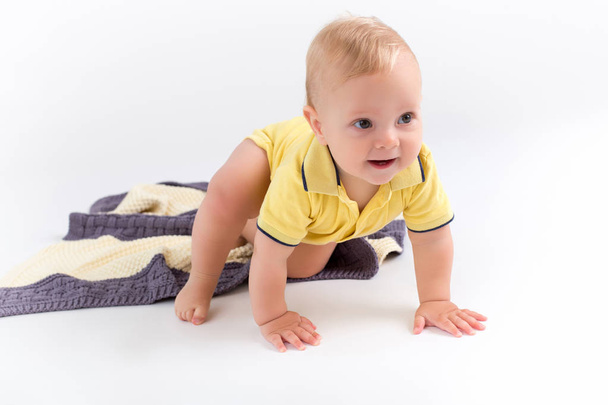 Niño lindo arrastrándose sobre la manta rayada de doble color sobre el fondo blanco
 - Foto, imagen
