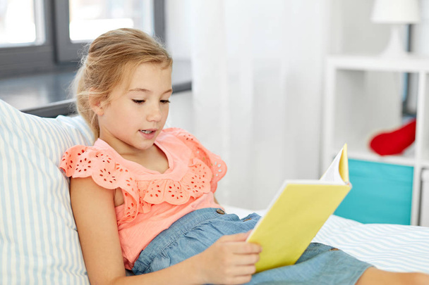 happy little girl reading book at home - Foto, imagen